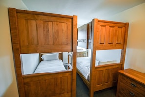 A room with two wooden bunk beds, a small wooden dresser, and a desk with a chair. - Stoney Creek Northstar 6 (Whistler)