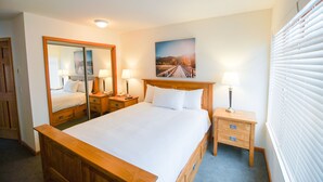 A neatly arranged hotel room with a large bed, bedside tables with lamps, a mirror, and a painting on the wall.