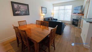 A dining area with a wooden table and chairs, a sofa, and a fireplace.