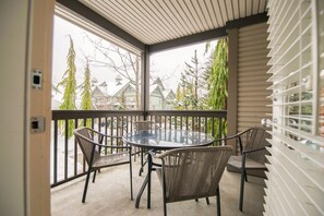A covered outdoor seating area with a round table and four chairs. - Stoney Creek Northstar 6 (Whistler)