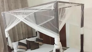 Una cama con dosel y cuatro columnas, con estructura de madera y ropa de cama blanca.