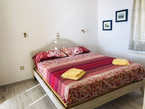 Ein Schlafzimmer mit einem hölzernen Bett, floralem Bettzeug und einem Fenster mit Vorhängen.