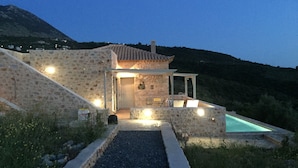 A stone house with a swimming pool, a covered patio, and a view of the surrounding hills. - Villa Luciana 'Fantastic sunsets by the pool' (Lagkada)