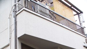 Un edificio residencial con un acceso amplio, un balcón pequeño y un escalón que lleva a la entrada.