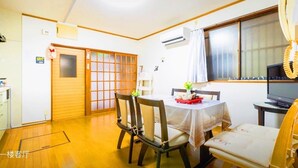 Una habitación con una mesa de comedor, sillas, un televisor y una puerta corredera.