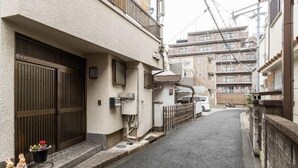 Una estrecha calle urbana con un edificio que tiene una gran puerta de madera y un pequeño porche.