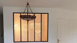 A room with a large window, a hanging light fixture, a door, and a table with chairs. - Duplex apartment 6 people Cannes Grand Parc (Cannes)