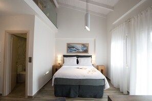 A bedroom with a large bed, a painting on the wall, and a window with curtains. - Villa Vilielmini (Ioannina)