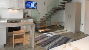 A modern kitchen with a built-in stove, a dining area with a wooden table, and a staircase leading to an upper level. - Villa Vilielmini (Ioannina)