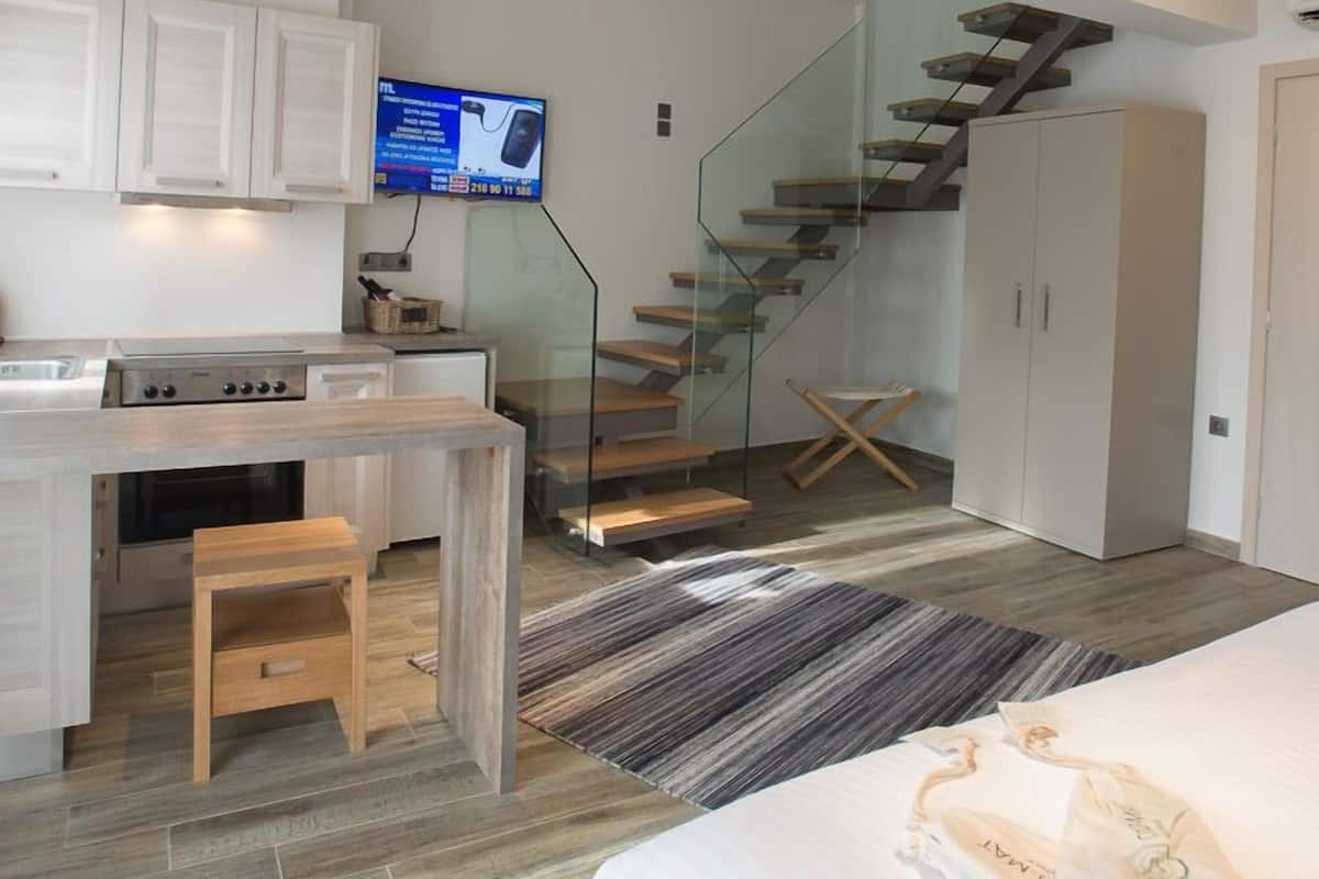 A modern kitchen with a built-in stove, a dining area with a wooden table, and a staircase leading to an upper level.