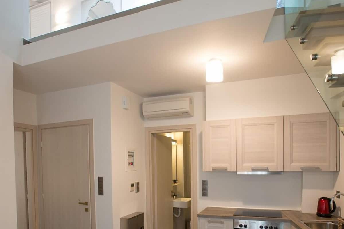 A modern kitchen with a built-in oven, a dining area with a table, and a staircase leading to an upper level.