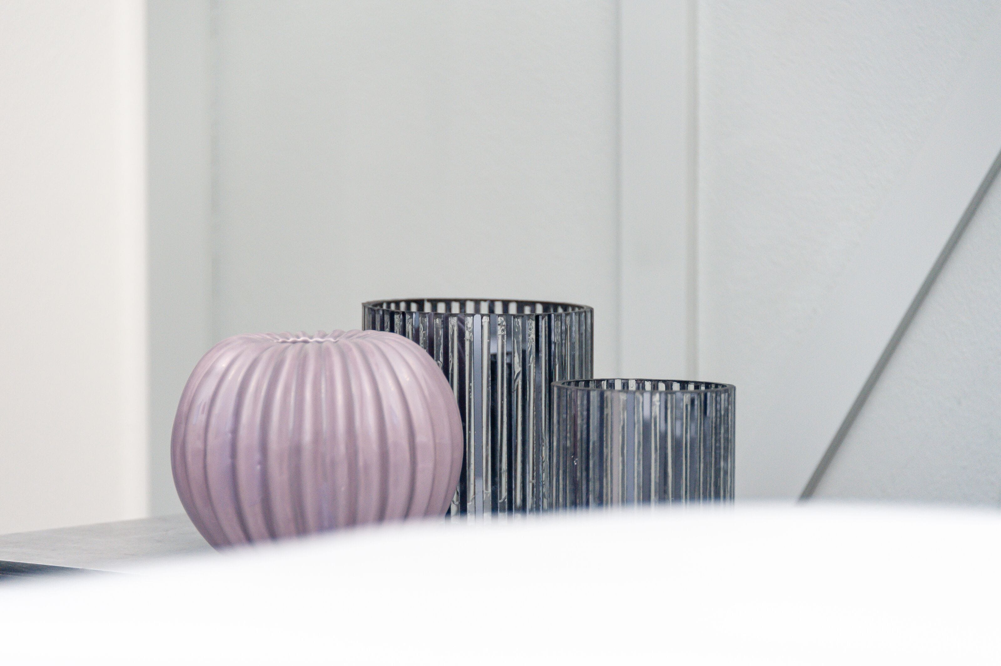 Three vases on a table against a white wall.
