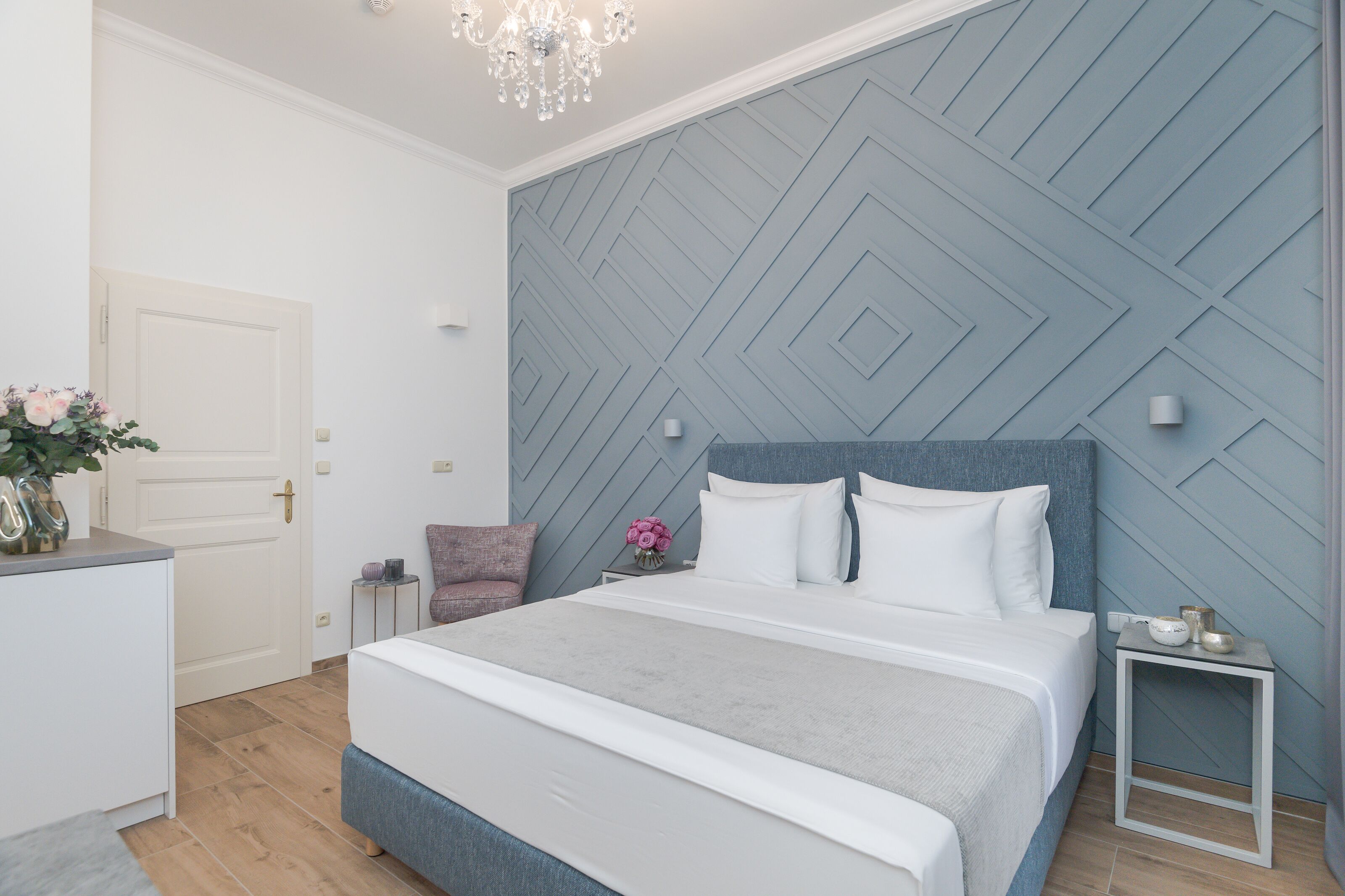 Un dormitorio con una cama, una mesita de noche, una silla y una puerta.