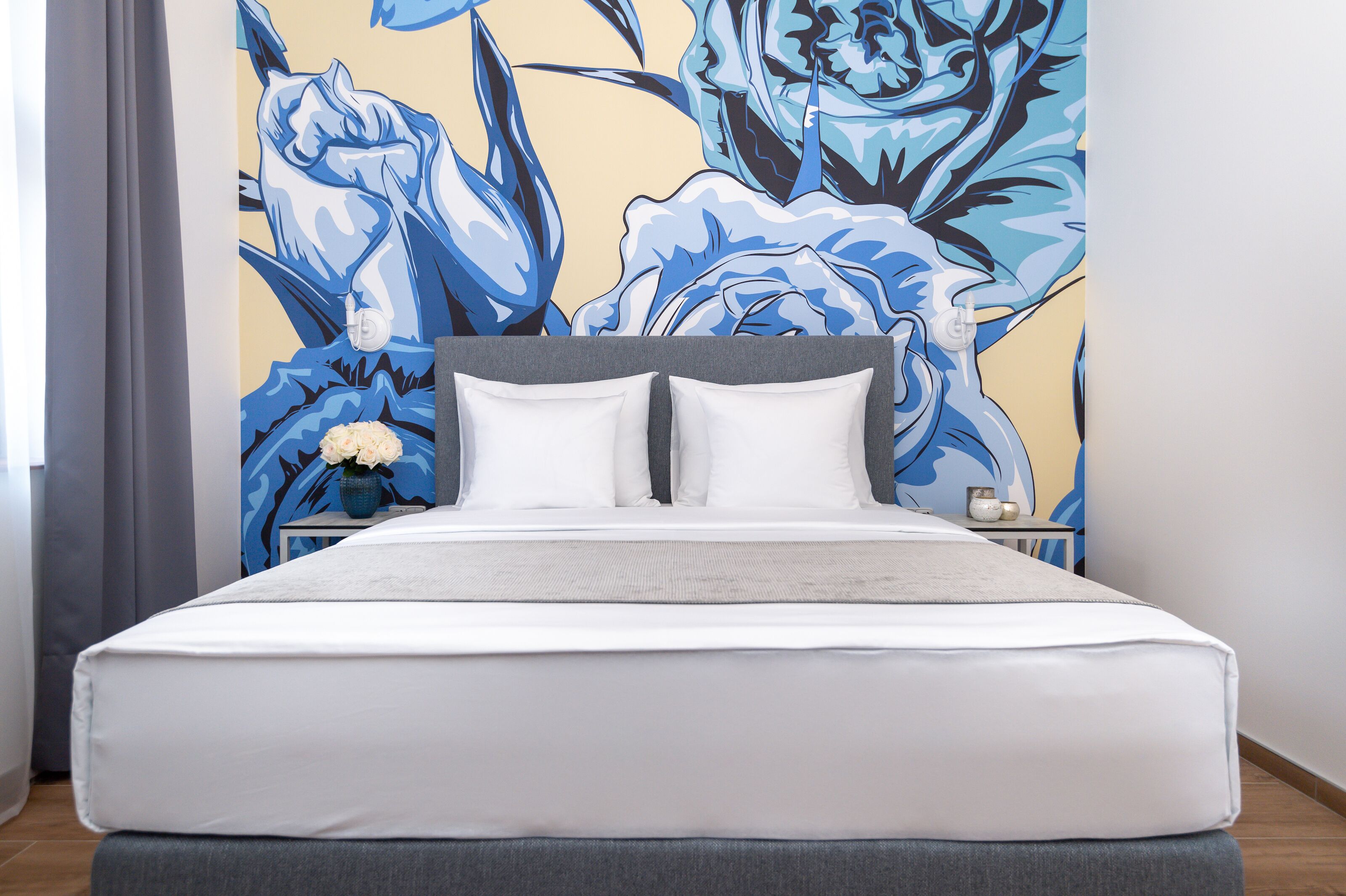 Une chambre à coucher moderne avec un grand lit, une table de chevet et une fresque murale.