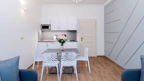 Una cocina moderna con armarios blancos, una mesa de comedor con sillas blancas y una araña.