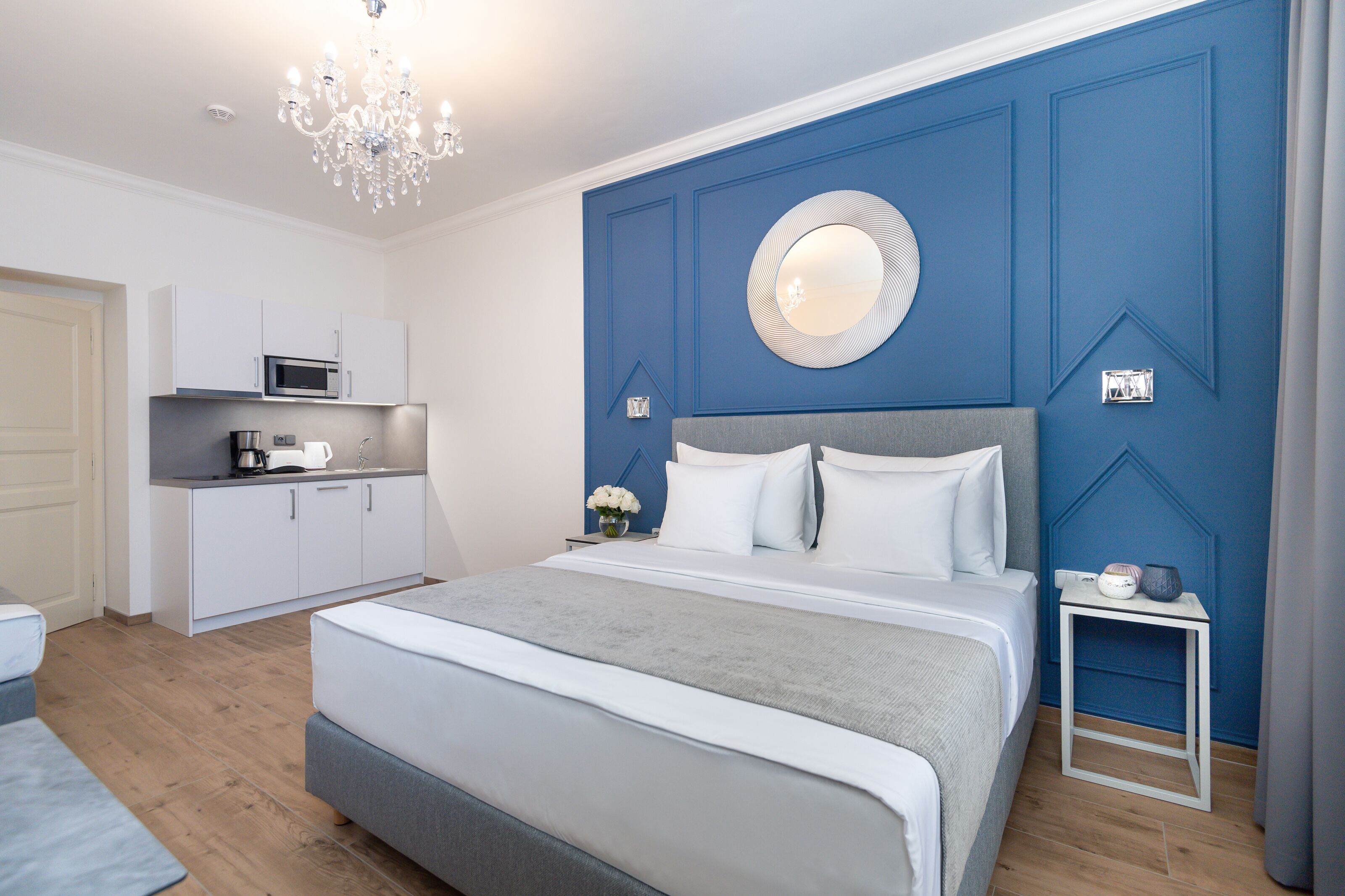 Ein modernes Schlafzimmer mit einem großen Bett, einem Nachttisch, einer Einbau-Mikrowelle und einer kleinen Küchenzeile.