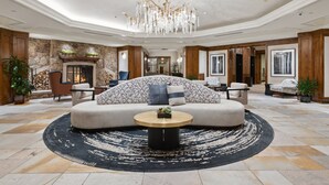 A spacious lobby with a large sofa, a round coffee table, and a chandelier. - The Aspen Mountain Residences 1 Bedroom Mountainside (Aspen)