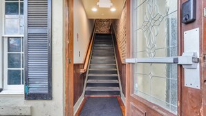 Una escalera estrecha que lleva a una puerta con un panel de vidrio y un tirador de metal.