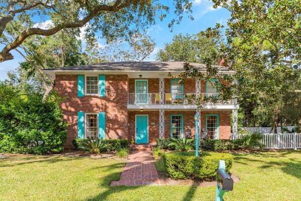A two-story brick house with green shutters, a front porch, and a mailbox. - LegaSea - Classic SSI, Pool, Steps to the Sand on East Beach (Saint Simons Island)