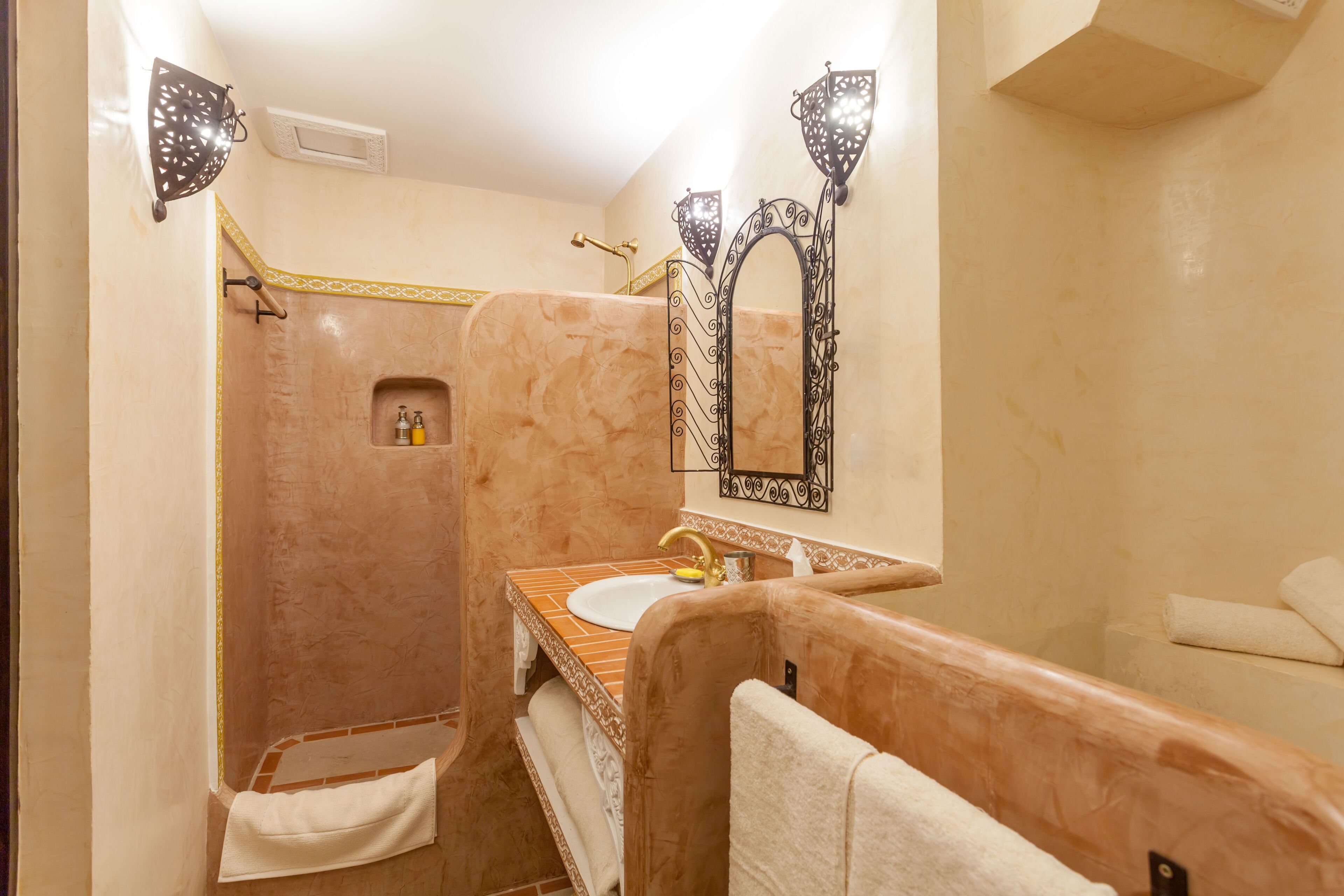 A bathroom with a marble sink, a shower, and a vanity with a mirror.