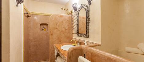 Une salle de bain avec un lavabo en marbre, une douche et un meuble-lavabo avec un miroir.