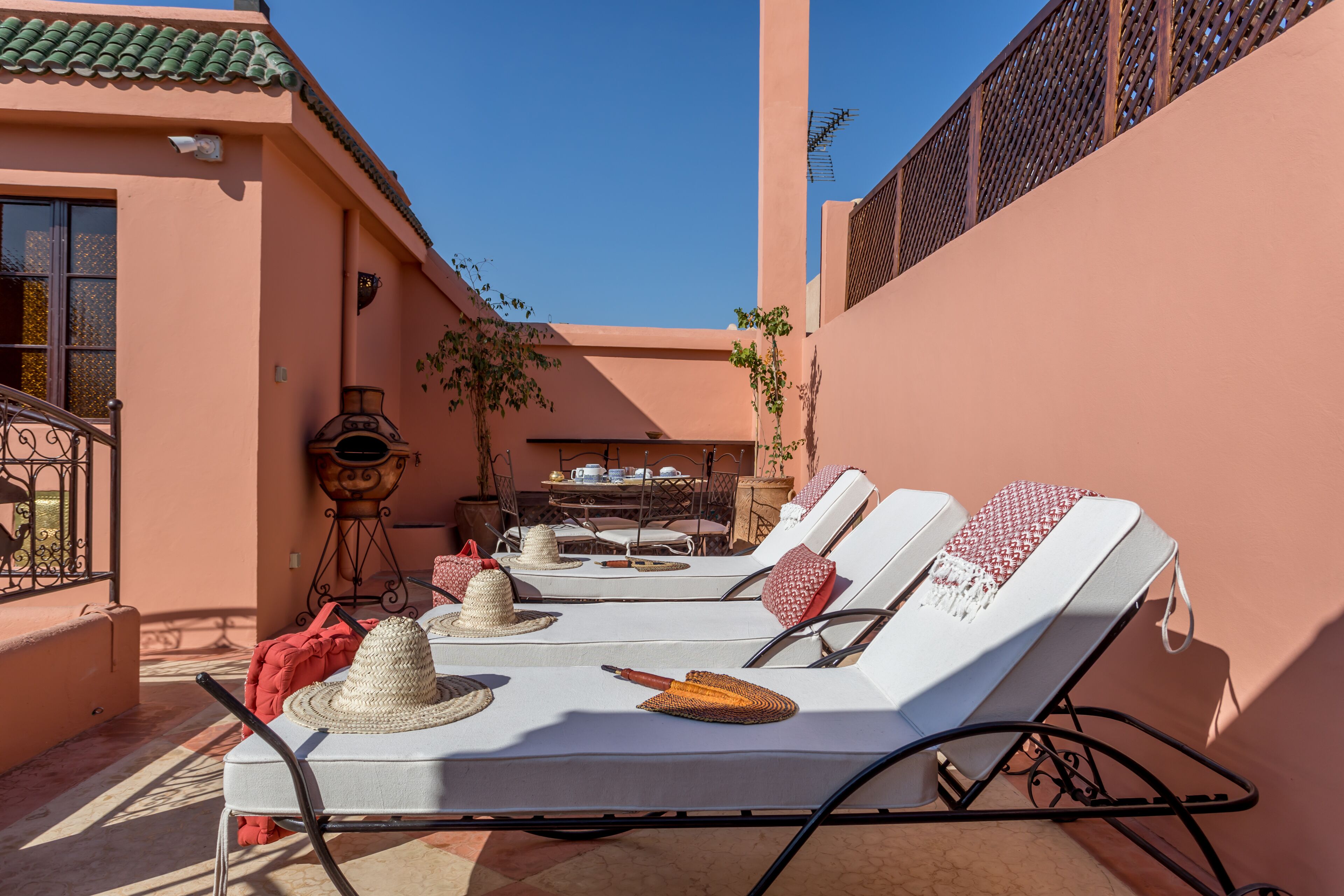 Een zonnig terras met lounge stoelen, een tafel en een decoratieve lamp.
