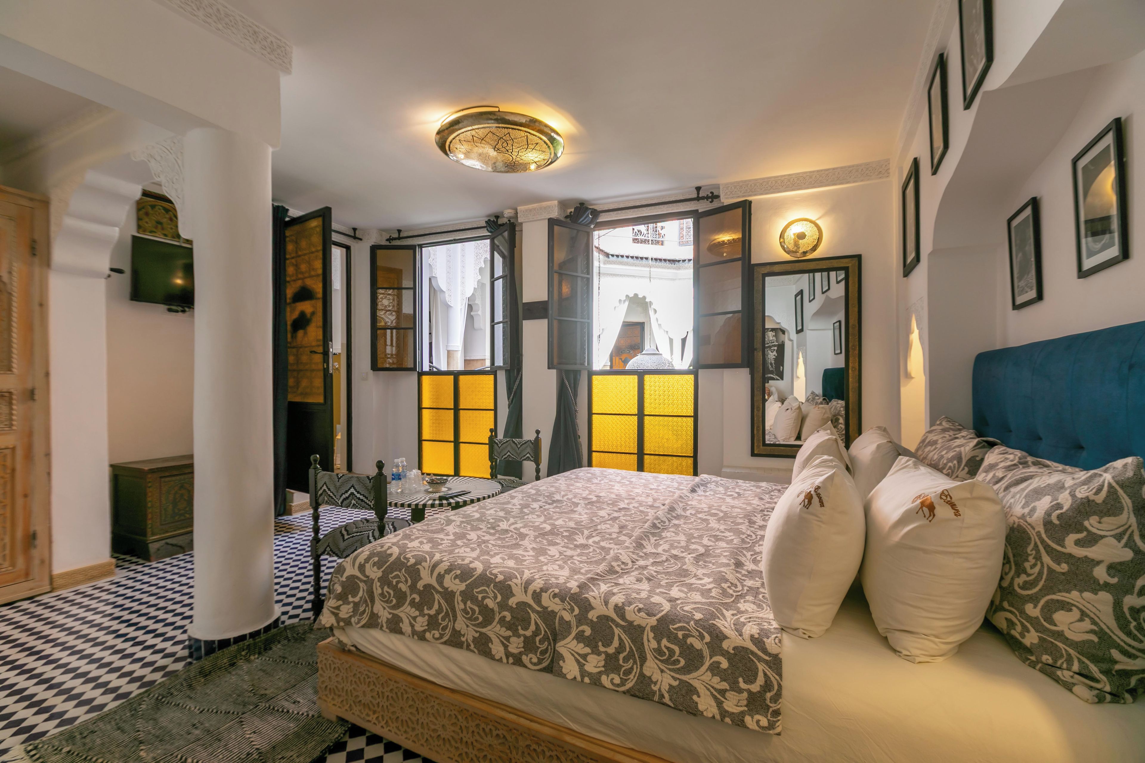 Una habitación de hotel con una cama, una silla, una mesa y vistas al exterior a través de una ventana.