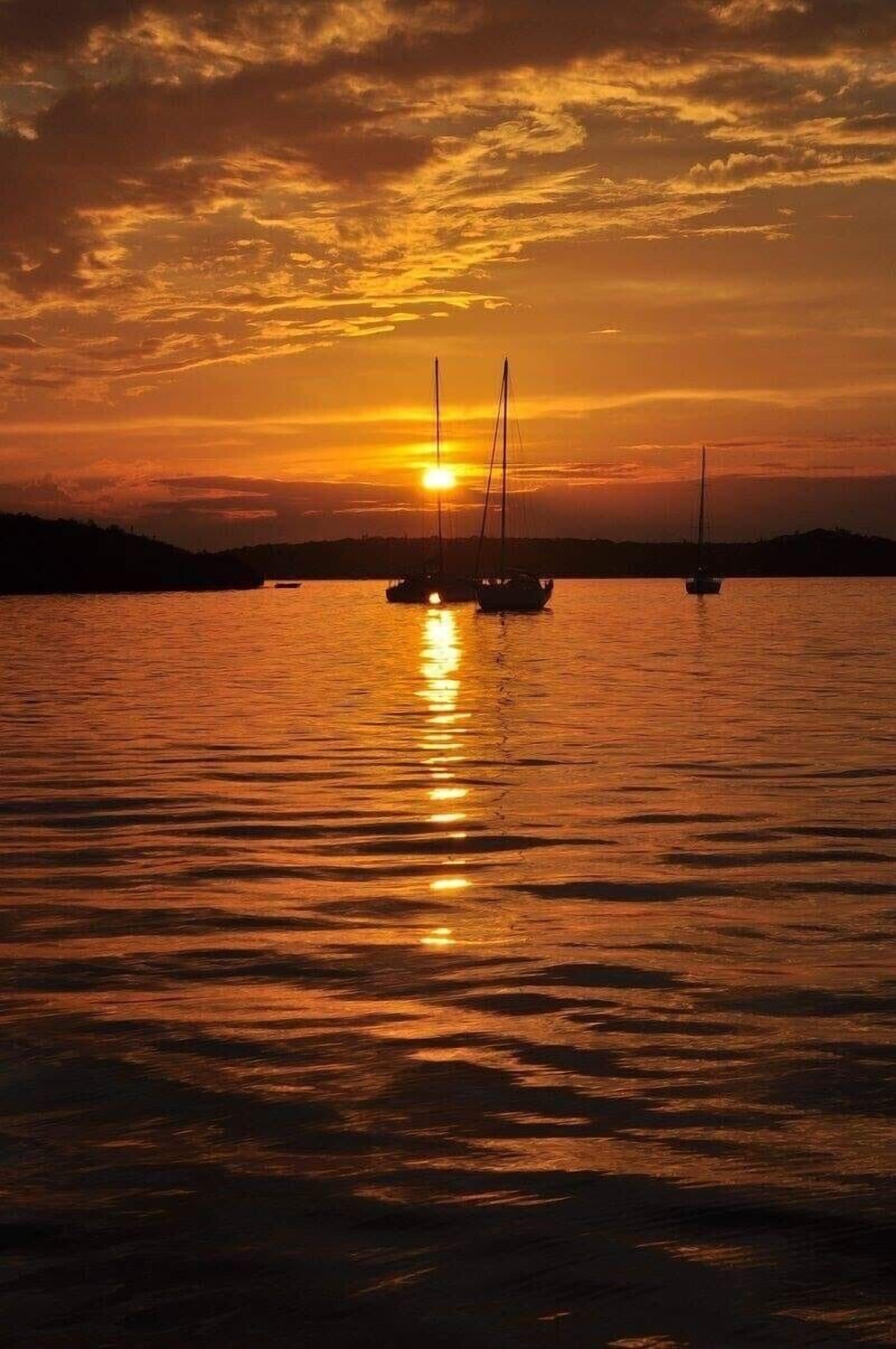 Un atardecer sobre un cuerpo de agua tranquilo con veleros.