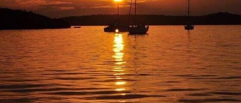 Un atardecer sobre un cuerpo de agua tranquilo con veleros.