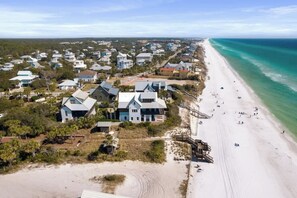 An aerial view of a coastal residential area with houses, a beach, and a lifeguard tower. - Redfish Village M1-309 (Santa Rosa Beach)