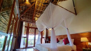 A room with a bed under a canopy, wooden walls, and large windows.