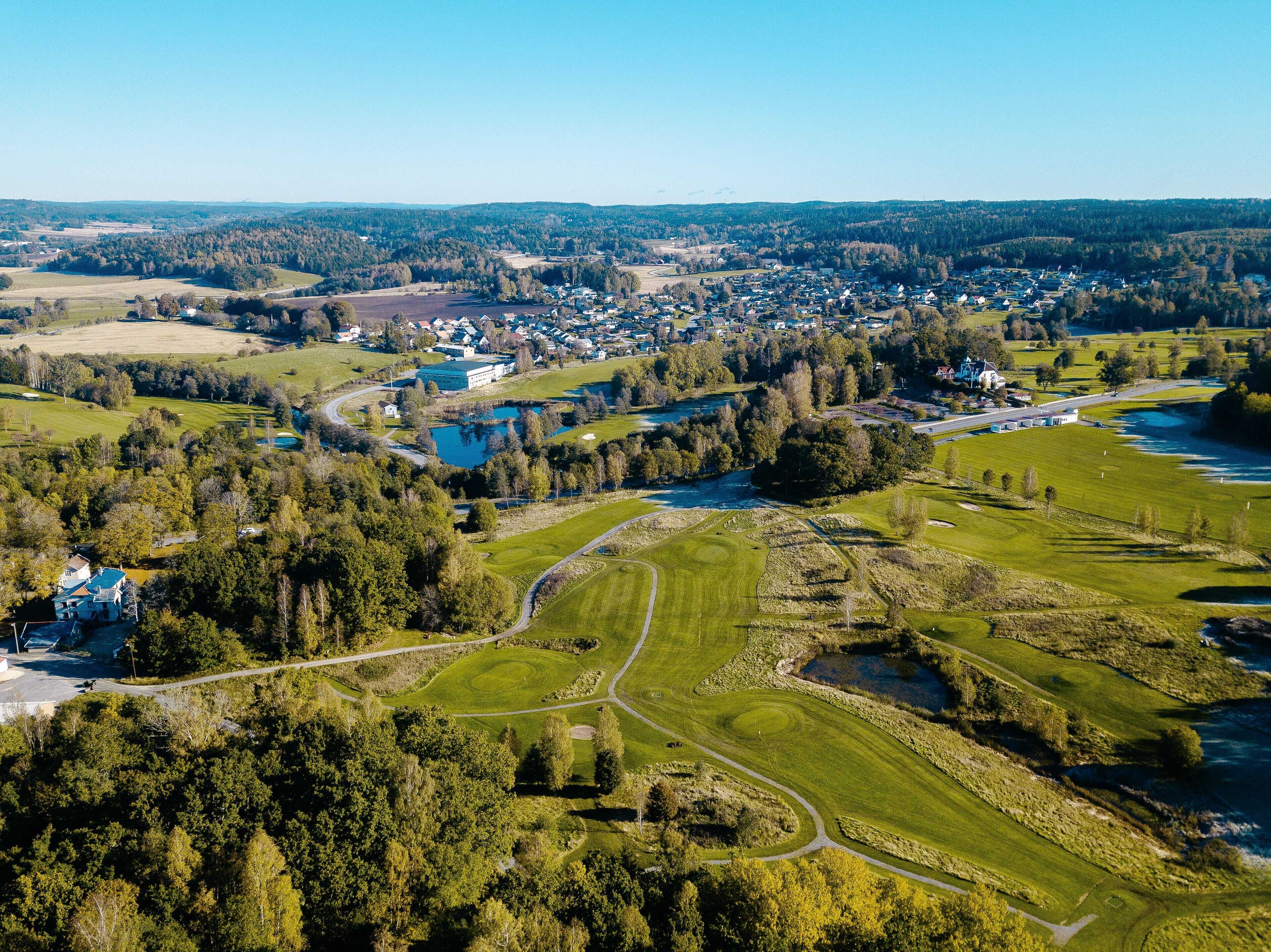 Vista aérea de una zona residencial con casas, un campo de golf y un río.