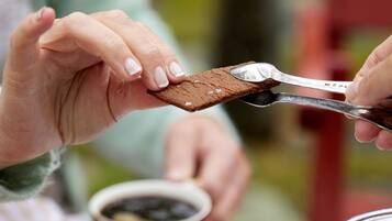 A person using scissors to cut a piece of chocolate.