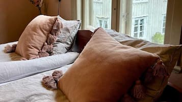 A bedroom with two beds, each with a large, fluffy pillow and a lamp on the wall.