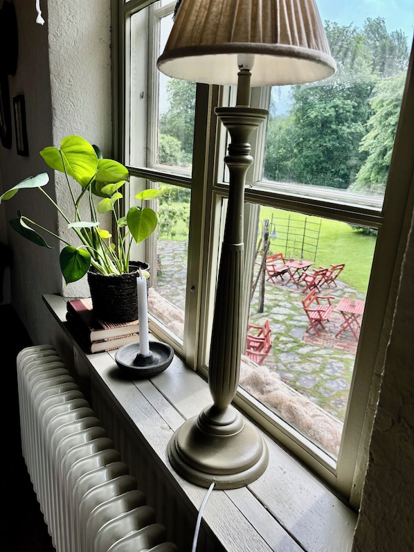 Una ventana con un radiador, una lámpara y una planta en maceta sobre el alféizar.