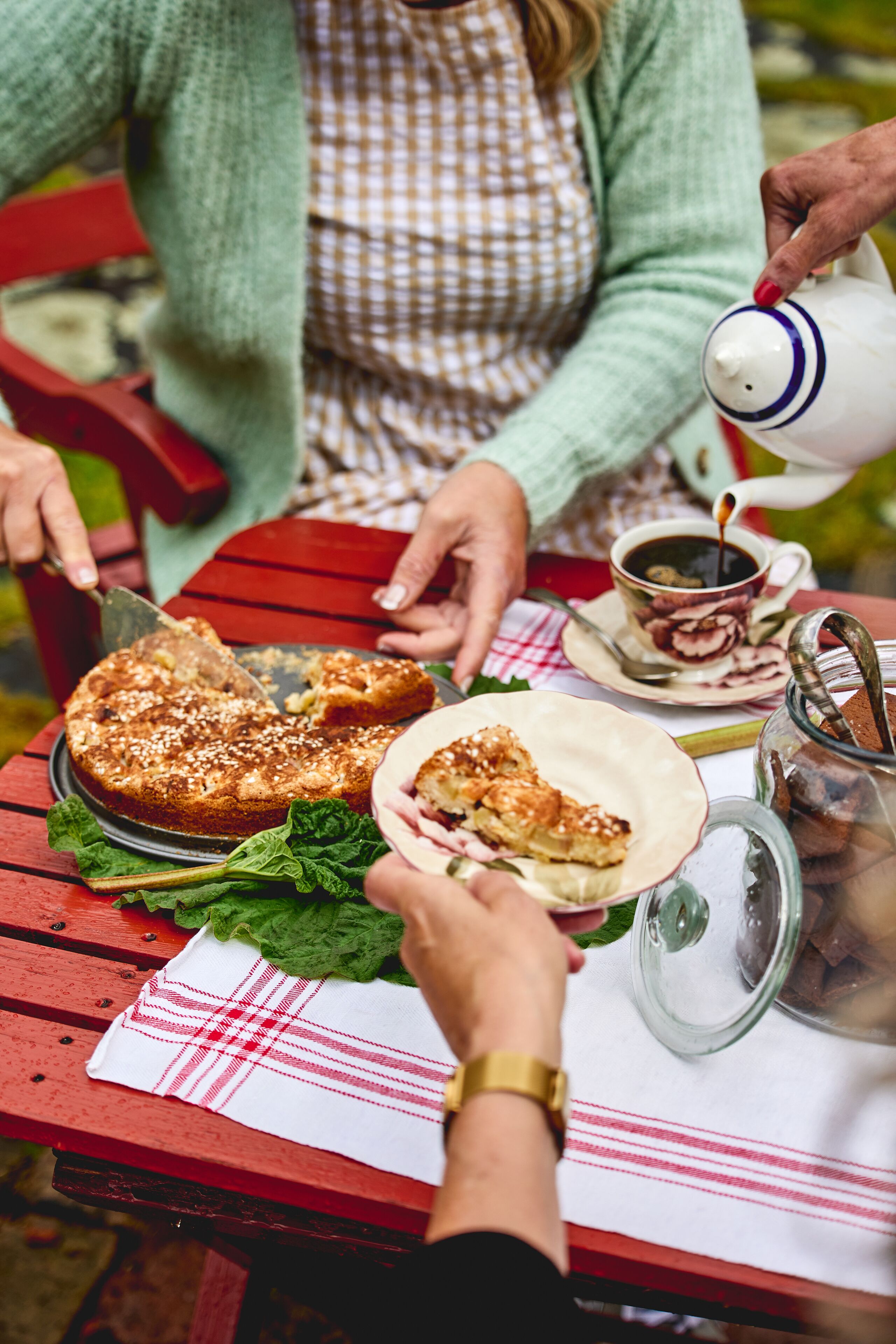 Uma mesa de jantar com um bolo, uma xícara de café e um jarro de café.