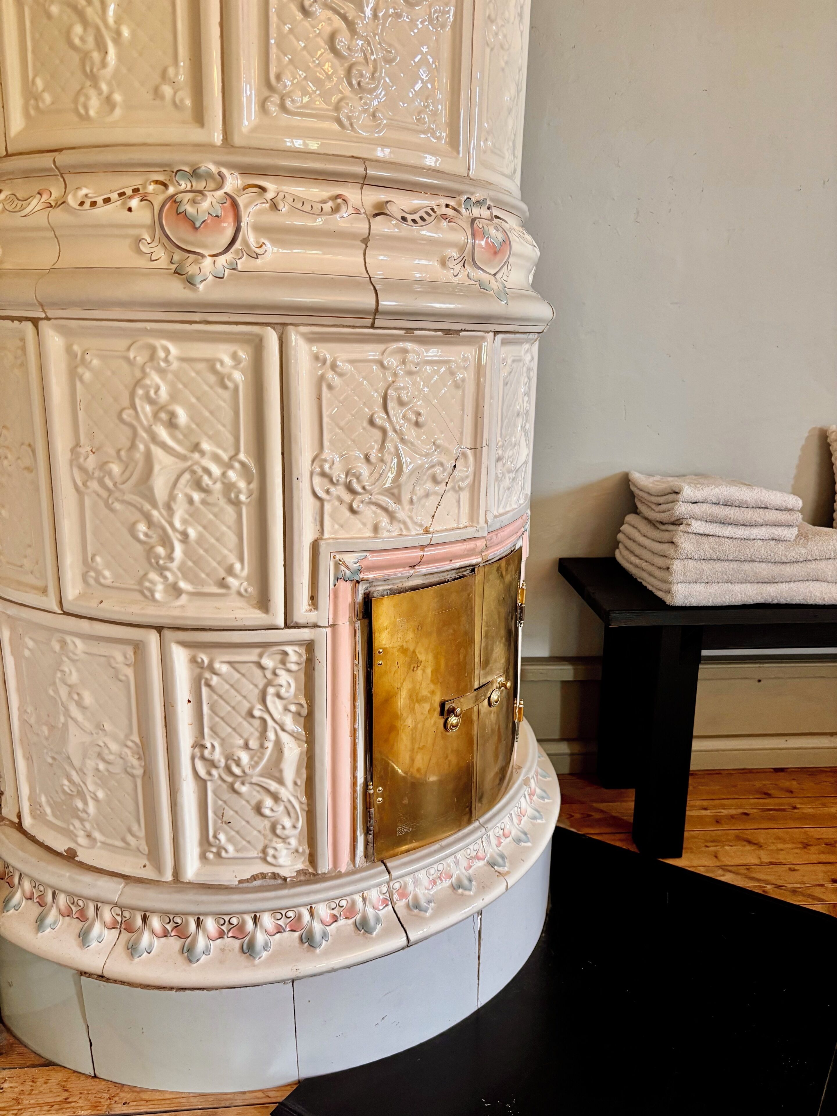 Une cheminée blanche et richement décorée, ornée de motifs complexes et dotée d’une porte dorée.