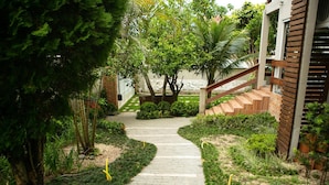 A pathway leading to a building with a wooden staircase and a brick wall. - Hostel House Santinho (Florianópolis)