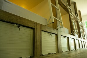 A row of closed garage doors with wooden beams and a ladder leaning against the wall.