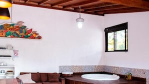 A room with a wooden ceiling, a mural of fruits and vegetables, a window, a brown sofa, and a small table with a white object on it. - Hostel House Santinho (Florianópolis)
