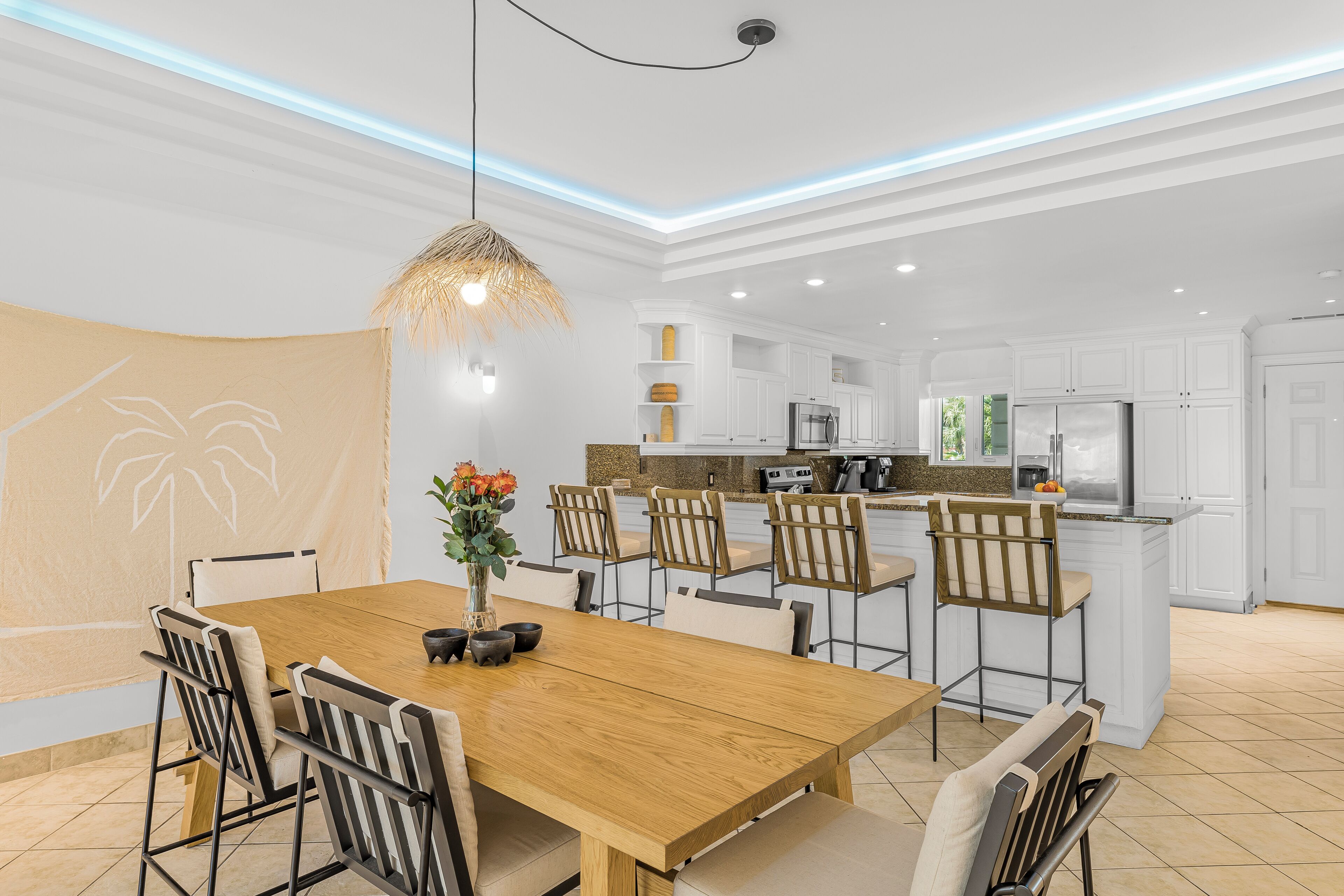 Una cocina moderna con armarios blancos, una mesa de comedor de madera y un colgador de luces.