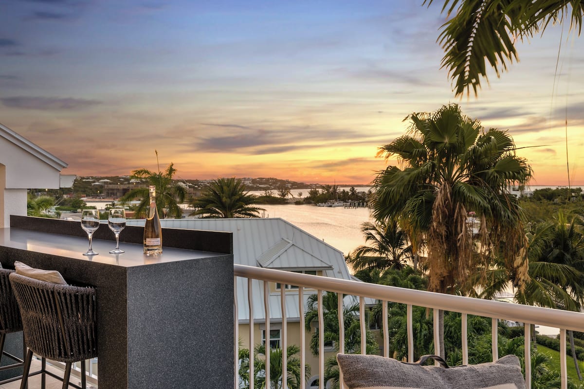 Un balcon avec un coin bar, deux chaises et une bouteille de champagne.