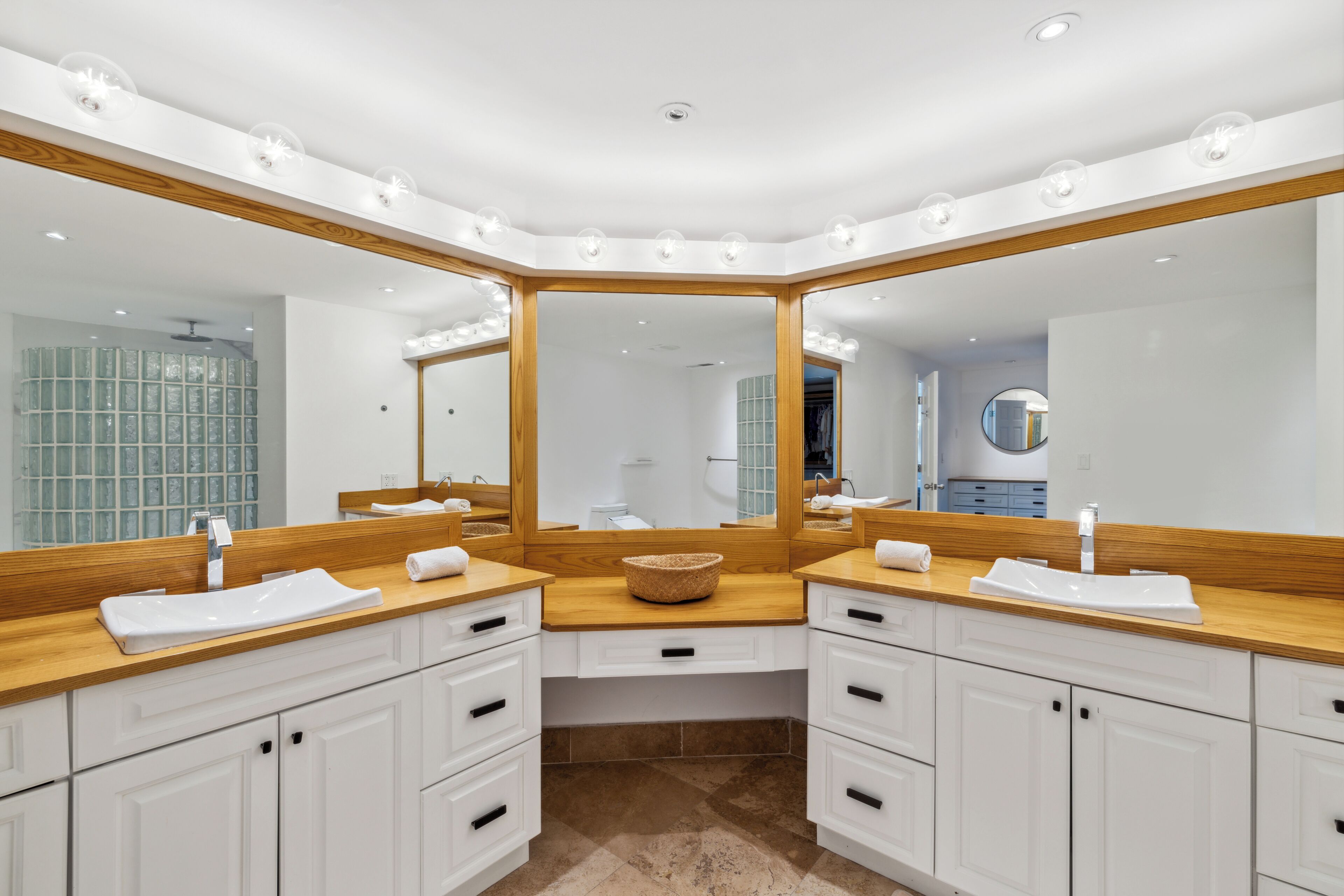 Une salle de bain moderne avec deux lavabos, de grands miroirs et des plans de travail en bois.
