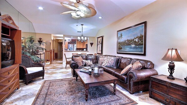 A living room with a sofa, coffee table, TV, and a painting on the wall.