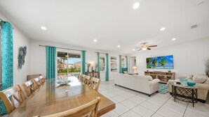 A spacious living area with a dining table, sofas, a TV, and a ceiling fan. - Charming Estate with Themed Bedrooms at Encore (Kissimmee)