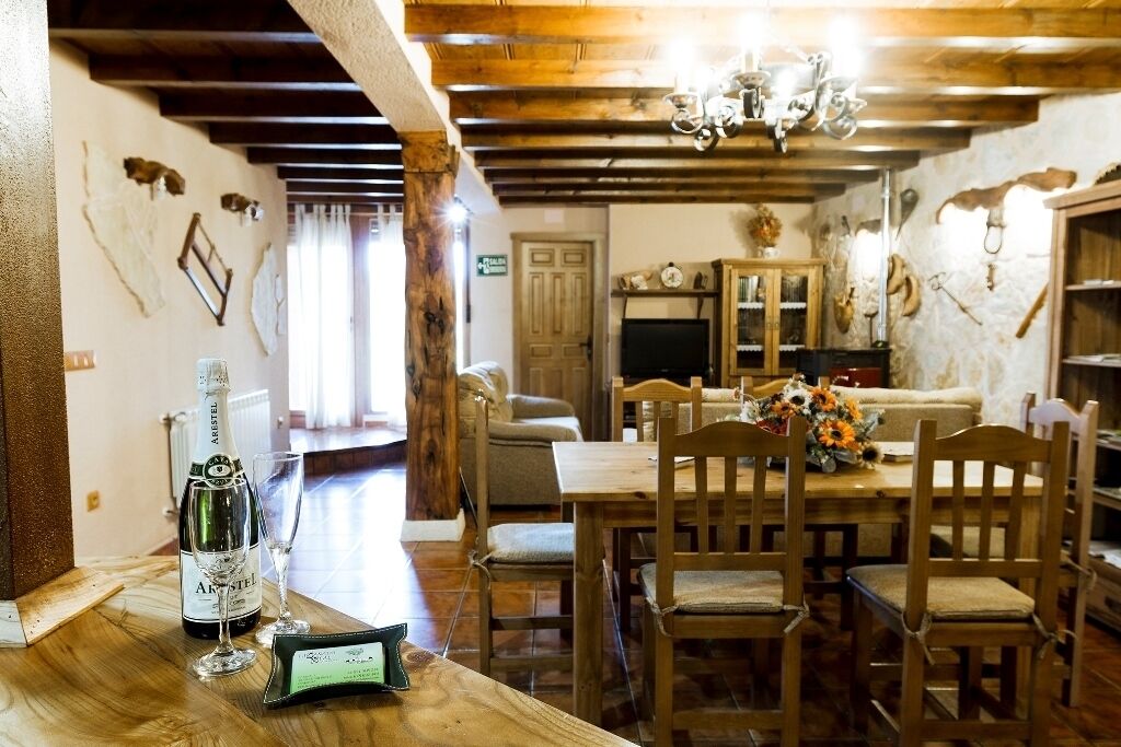 Un coin repas rustique, avec des meubles en bois, un lustre et des peaux d’animaux accrochées aux murs.