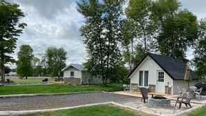 A campsite with two cabins, a fire pit, and outdoor seating. - Cozy little cottage with big memories (Campbellford)