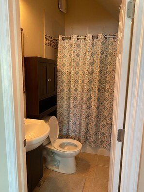 A small bathroom with a toilet, sink, and shower curtain.