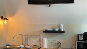 Eine kompakte Küche mit Einbaukühlschrank, Mikrowelle, Toaster und einem flachbildfernseher an der Wand.