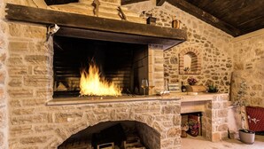 Une cheminée en pierre avec un feu de bois, une cheminée en bois et un intérieur rustique.